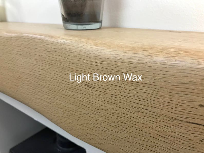 May include: Close-up of a light brown wooden shelf with a natural grain pattern. The text "Light Brown Wax" is visible on the shelf. A glass container sits on the shelf.