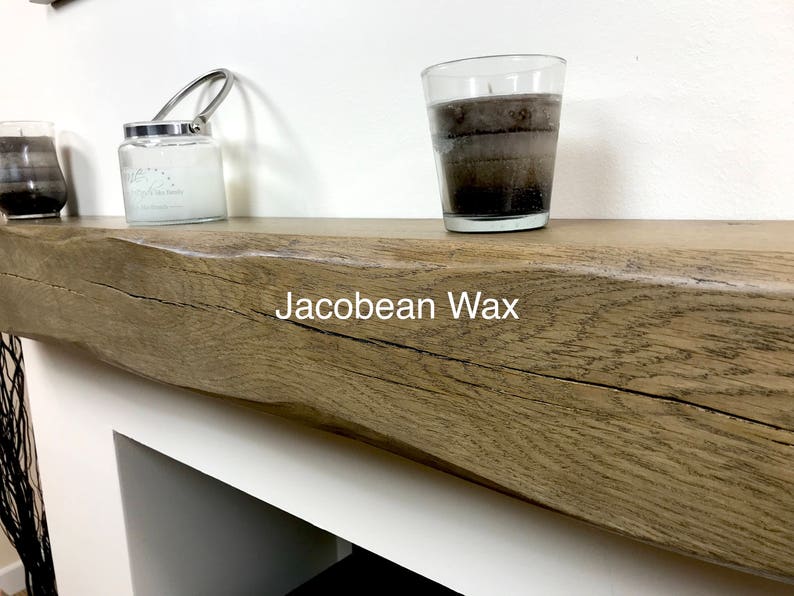 May include: A wooden mantel with a rough, textured surface. Two candles in glass containers and a jar candle with a metal handle are on the mantel. The text "Jacobean Wax" is visible on the mantel.