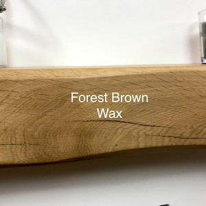 May include: A rustic, wooden shelf with a natural, light brown finish. The text "Forest Brown Wax" is printed on the shelf. A glass jar and a candle are on the shelf.