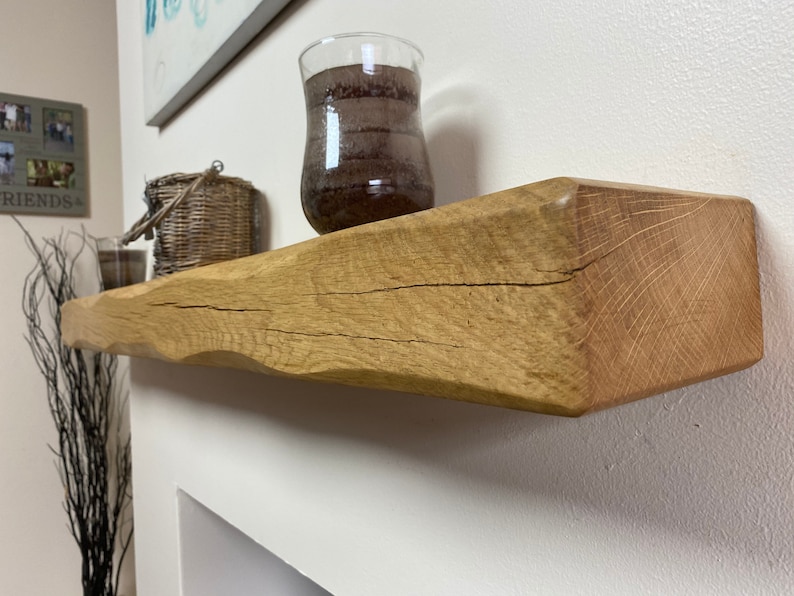 May include: A natural wood floating shelf with a live edge. The shelf is light brown with visible wood grain and a rough, textured surface. A decorative glass vase and a woven basket sit on the shelf, adding a rustic touch to the decor.