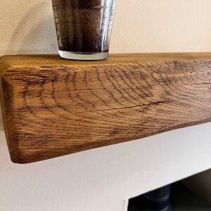 May include: A close-up of a rustic wooden shelf with a natural wood finish. The shelf is made of reclaimed wood and has a unique grain pattern. The shelf is perfect for displaying decorative items or plants.