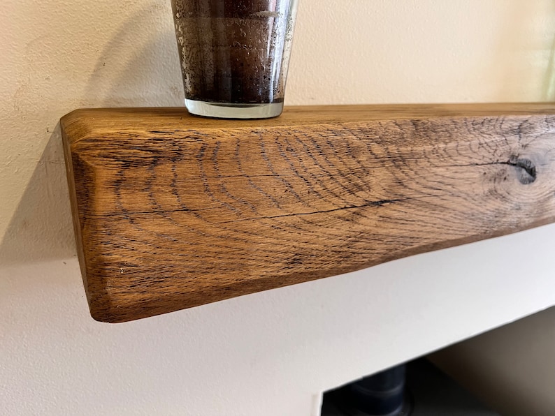 May include: A close-up of a rustic wooden shelf with a natural wood finish. The shelf is made of reclaimed wood and has a unique grain pattern. The shelf is perfect for displaying decorative items or plants.