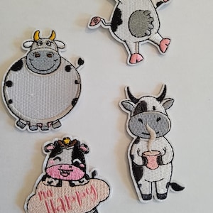 Peut inclure: Quatre patchs brodés thermocollants représentant des vaches de dessin animé. Une vache porte un chapeau de cowboy et tient un nuage avec le mot "Happy" dessus. Une autre vache tient une tasse de lait. Les deux autres vaches sont dans des poses différentes.