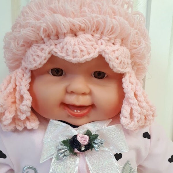 Children's knitted hat-wig with bows for a photo shoot in a beautiful pink color