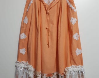 Falda larga de mujer en lino natural color melocotón con bordado blanco y volante de estilo bohemio.