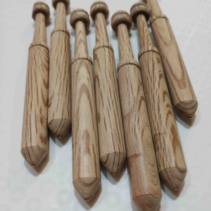 Könnte beinhalten: Ein Satz von acht Stricknadeln aus Holz mit einer spitzen Spitze und einem abgerundeten Kopf. Die Nadeln sind aus hellbraunem Holz mit dunkelbraunen Streifen.