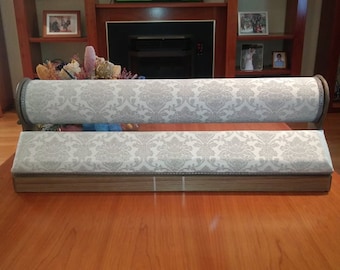 May include: A white and gray patterned fabric covered jewelry display stand with two rolling sections. The stand is made of wood and has a silver trim.