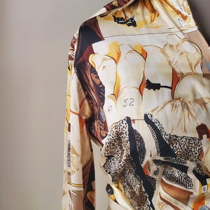 Puede incluir: Camisa de manga larga con un estampado &uacute;nico. La camisa presenta un fondo beige con un collage de figuras, estampado de leopardo y el n&uacute;mero "52". La paleta de colores incluye beige, marr&oacute;n, negro y amarillo.