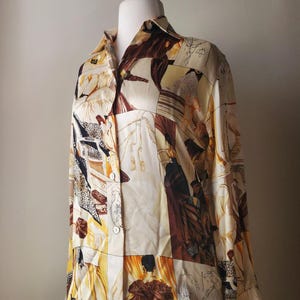 Puede incluir: Blusa abotonada con dise&ntilde;o de patchwork con figuras en tonos marr&oacute;n, beige y amarillo. La camisa de manga larga tiene cuello y se muestra en un maniqu&iacute;.