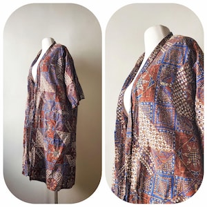 May include: A patterned kimono-style robe in shades of brown, blue, and white. The robe features a geometric design with squares and floral patterns. The garment is displayed on a mannequin, showcasing its open front and short sleeves.