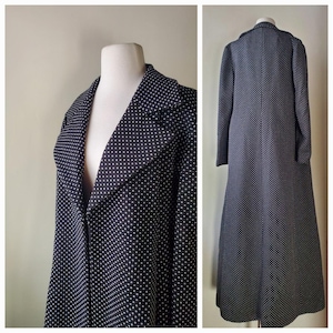 May include: A long, dark navy blue coat with a white polka dot pattern. The coat has a wide lapel collar and long sleeves. The coat is displayed on a mannequin.