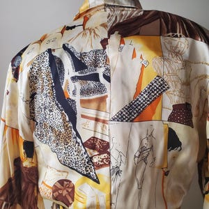 Puede incluir: Una blusa color crema con un dise&ntilde;o de patchwork &uacute;nico. La blusa presenta una variedad de patrones, incluyendo estampado de leopardo, formas geom&eacute;tricas y figuras esbozadas. La paleta de colores incluye crema, marr&oacute;n, negro y acentos naranja. La blusa tiene mangas largas y cuello.