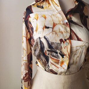 Puede incluir: Una camisa vintage estampada con fondo crema. La camisa presenta un estampado de figuras, estampado de leopardo y dise&ntilde;os abstractos en marr&oacute;n, negro y naranja. Se combina con una falda color crema, creando una est&eacute;tica retro.