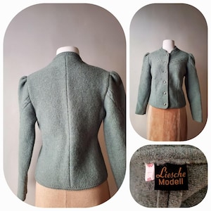 May include: A light green wool jacket with a high collar and puffed sleeves. The jacket has a button-up front and a tailored fit. The label reads "Liesche Modell". The jacket is displayed on a mannequin.