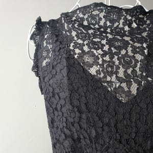 May include: A black lace top with a floral pattern. The sleeveless top features a high neckline and a delicate, textured design. The lace is intricately detailed, creating a sophisticated and elegant look.