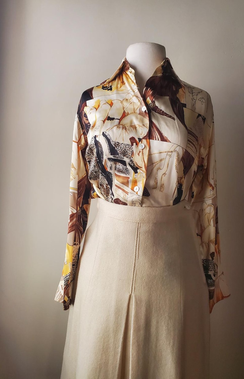 Puede incluir: Conjunto vintage de dos piezas que consta de una blusa estampada y una falda. La blusa tiene una base crema con un dise&ntilde;o marr&oacute;n y beige. La falda es de color beige claro liso. El conjunto se exhibe en un maniqu&iacute;.