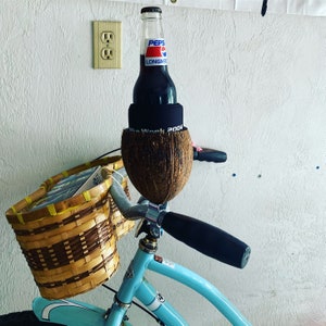 May include: A blue bicycle with a brown wicker basket and a coconut holding a bottle of Pepsi. The bottle is wrapped in a black band with the text "Fun Week 2004".