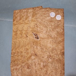 Puede incluir: Cuatro piezas de chapa de madera con un patrón de raíz. La madera es de color marrón claro con remolinos marrones más oscuros. La chapa mide 15x25 pulgadas.