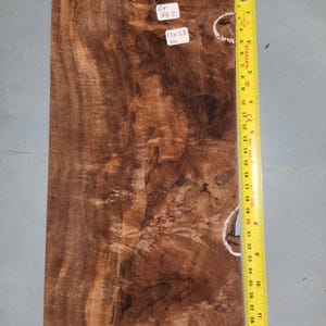 Puede incluir: Una chapa de madera con un patrón de chapa marrón y negro. La chapa mide 13 pulgadas por 2,8 pulgadas y está etiquetada como "GT 442".