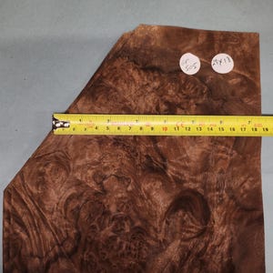 Puede incluir: Un primer plano de una chapa de madera con un patrón de chapa marrón y marrón rojizo. La chapa mide aproximadamente 45,7 cm por 33 cm. El texto "GT 505 34 18" está escrito en una etiqueta blanca.