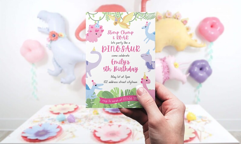 May include: A birthday invitation with a dinosaur theme. The invitation reads "Stomp Chomp & ROAR, let's party like a DINOSAUR, come celebrate Emily's 5th Birthday." The invitation is held in a hand, with dinosaur balloons in the background.