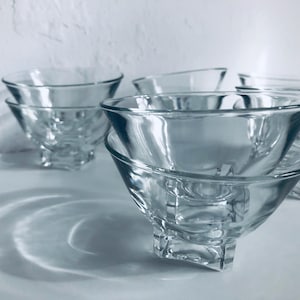 Op de afbeelding: Set van zes glazen kommen met een vierkante basis. De kommen zijn op elkaar gestapeld.