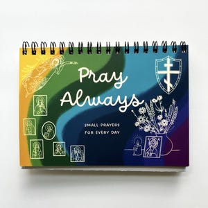 Puede incluir: Un libro de oraciones encuadernado en espiral con las palabras "Pray Always" en escritura blanca. La portada presenta ilustraciones de ángeles, iconos y flores sobre un fondo colorido de amarillo, azul, verde y morado.
