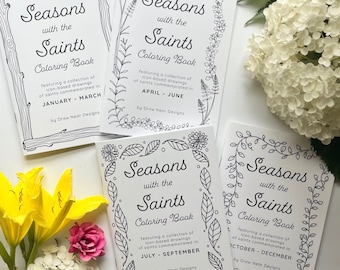 Puede incluir: Tres libros para colorear en blanco y negro con el título "Seasons with the Saints Coloring Book". Cada libro presenta una estación diferente y los meses asociados a esa estación. Los libros están sobre una superficie blanca con flores.