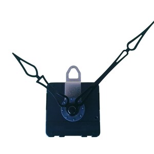Può includere: Un meccanismo di orologio nero con lancette delle ore e dei minuti nere. Il meccanismo dell'orologio è quadrato con un gancio in metallo argentato e un dettaglio circolare blu e argento. Le lancette hanno punte decorative.