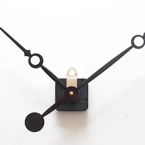 Può includere: Lancette nere con un design circolare e un meccanismo dell'orologio quadrato. Le lancette sono lunghe e sottili, con un'estetica minimalista. Le lancette dell'orologio sono su uno sfondo bianco.