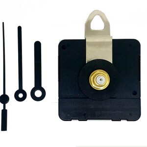 Può includere: Un meccanismo di orologio nero con una staffa in metallo argentato e un dado color oro. Tre lancette nere di diverse lunghezze sono a sinistra del meccanismo. Le lancette includono una lancetta dei secondi, una lancetta dei minuti e una lancetta delle ore.