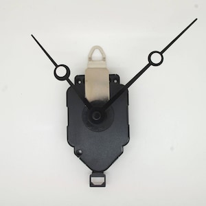 May include: Black clock hands with a white plastic mounting bracket attached to a black clock mechanism.
