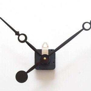 May include: Black clock hands with a white center and a black clock mechanism.