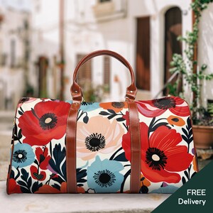 Könnte beinhalten: Eine braune Leder-Reisetasche mit einem Blumendruck mit roten, rosa und blauen Blumen. Die Tasche hat einen weißen Hintergrund und braune Lederriemen.