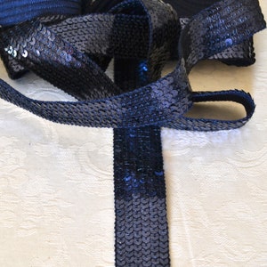 Peut inclure: Ruban de sequins bleu marine, une garniture décorative avec une surface chatoyante. Le ruban est densément recouvert de petits sequins ronds, créant un effet texturé. Le ruban mesure environ 2,5 cm de large.