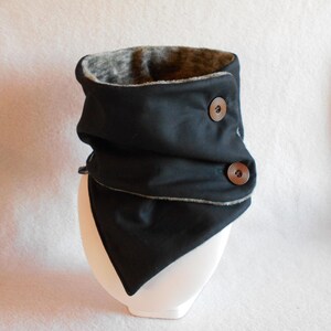 Puede incluir: Cuello de lana negro con forro de borreguito gris y dos botones marrones.