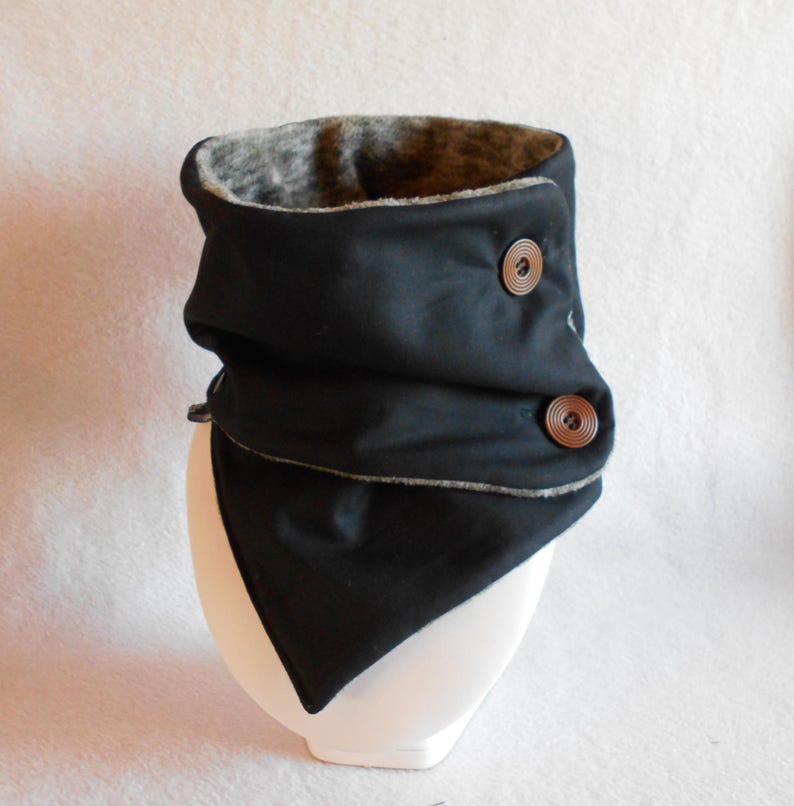 Puede incluir: Cuello de lana negro con forro de borreguito gris y dos botones marrones.