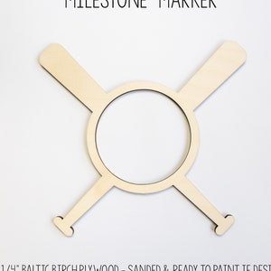 May include: Wooden milestone marker shaped like two crossed baseball bats with a circle in the center. The marker is made of 1/4 inch Baltic birch plywood and is sanded and ready to paint. "MILESTONE MARKER" and "OKITTYANDBOBOSDESIGNS" are printed on the marker.