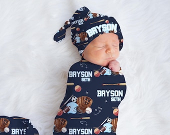 May include: A navy blue baby swaddle and hat set with a baseball theme. The swaddle and hat are covered in a pattern of baseballs, bats, gloves, and the names "Bryson Seth".