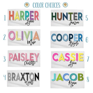 Op de afbeelding: Een tabel met acht verschillende kleurkeuzes voor gepersonaliseerde handdoeken. Elke keuze heeft een naam in kleurrijke blokletters met een kleinere naam eronder. De namen zijn: Harper, Hunter, Olivia, Cooper, Paisley, Cassie, Braxton en Jacob.