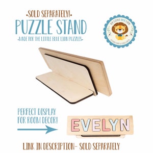 May include: A wooden puzzle stand with a light-colored finish, designed to display puzzles. The stand is angled for optimal viewing and features a rectangular base. Text on the image reads "PUZZLE STAND" and "EVELYN".
