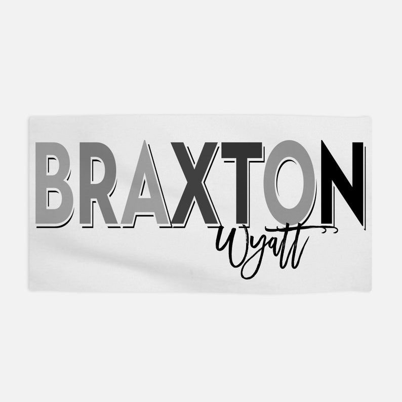 Op de afbeelding: Witte handdoek met de naam "Braxton Wyatt" in zwarte en grijze letters.