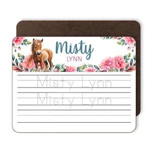 May include: A rectangular white practice writing board featuring a brown pony illustration, pink floral accents, and the name Misty Lynn in blue and pink text. The board includes two lines of dotted text reading Misty Lynn for tracing practice.