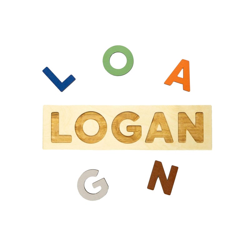 May include: Wooden name puzzle spelling "LOGAN" with individual colorful letters. The puzzle base is light wood with the name carved out. The letters are in various colors: blue, green, orange, gray, and brown. A fun educational toy.
