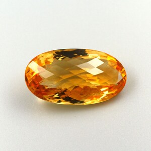 May include: A large, oval-shaped, faceted citrine gemstone with a warm, golden-yellow hue.