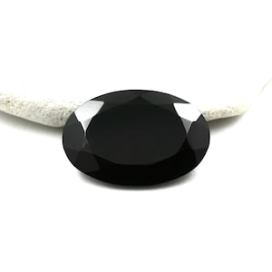 May include: A black oval-shaped gemstone with a faceted cut.