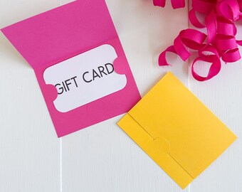 May include: A bright pink gift card holder with a white gift card that reads "GIFT CARD" is open, next to a closed yellow gift card holder. The image also shows a pink ribbon and the text "SVG • DXF • PNG • JPG".