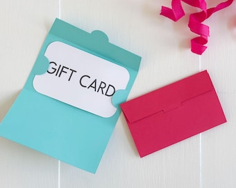 May include: A light blue gift card holder with a white gift card that reads "GIFT CARD". A small red envelope is next to the holder. Pink ribbon curls in the upper right corner. The words "SVG • DXF • PNG • JPG" are at the top.