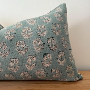 May include: A light blue pillow with a white and black floral pattern.