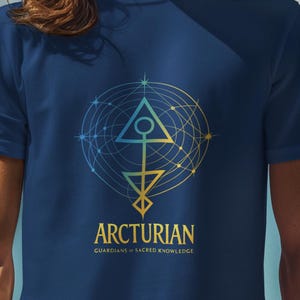 May include: A navy blue t-shirt featuring a geometric design in yellow and blue, with the word "ARCTURIAN" in white. The shirt is worn by a person with long brown hair and a grey beanie, against a blue sky.